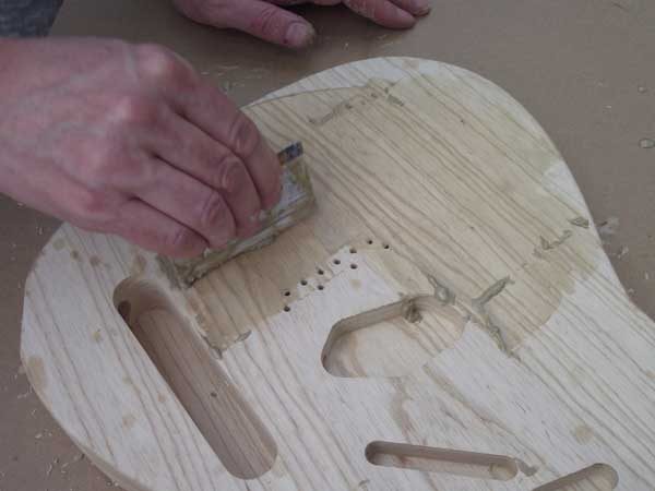 Applying grain filler to the front of the guitar body